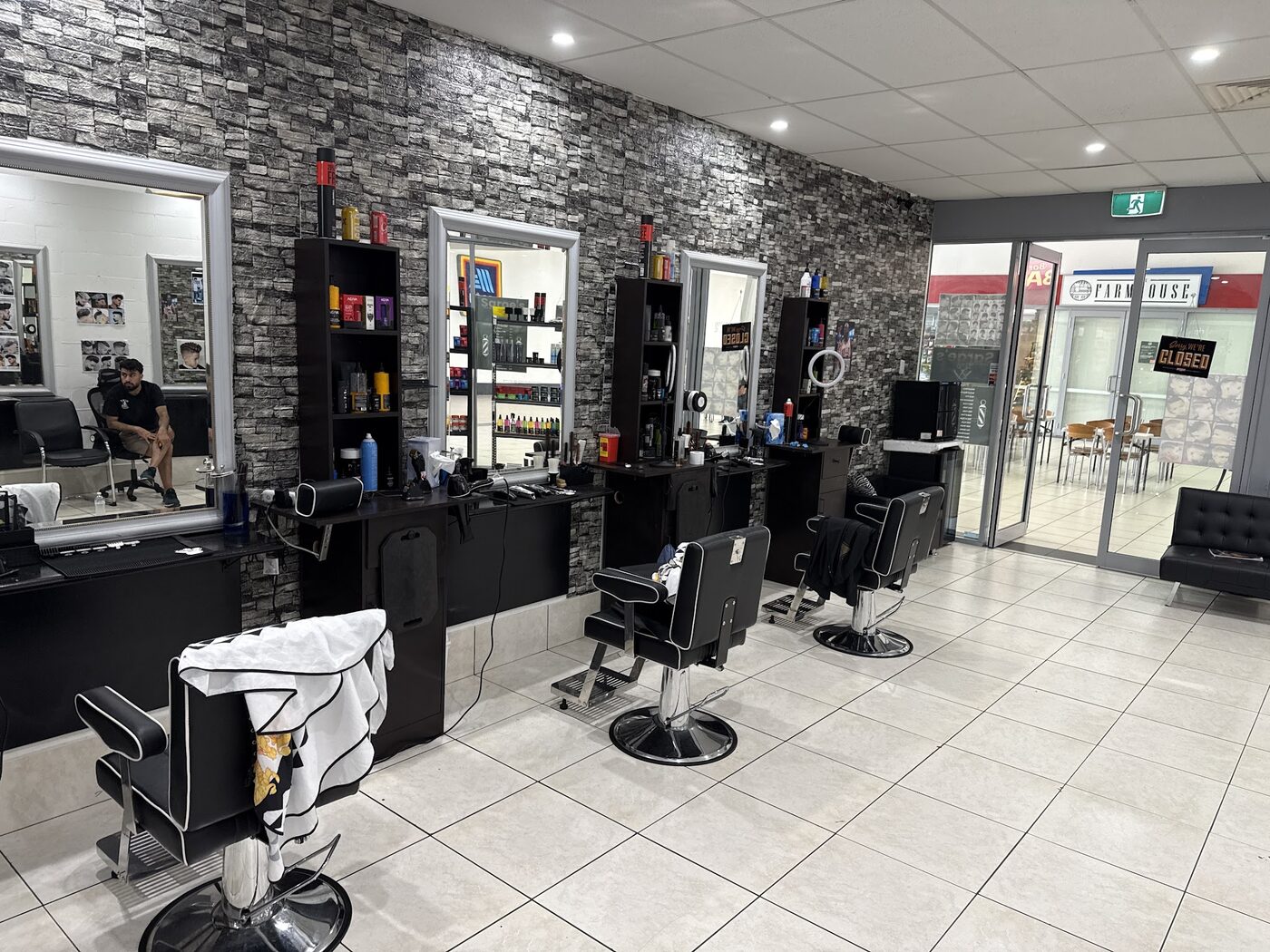 Inside Nextcut Barber Shop: three barber chairs in front of a grey stone feature wall