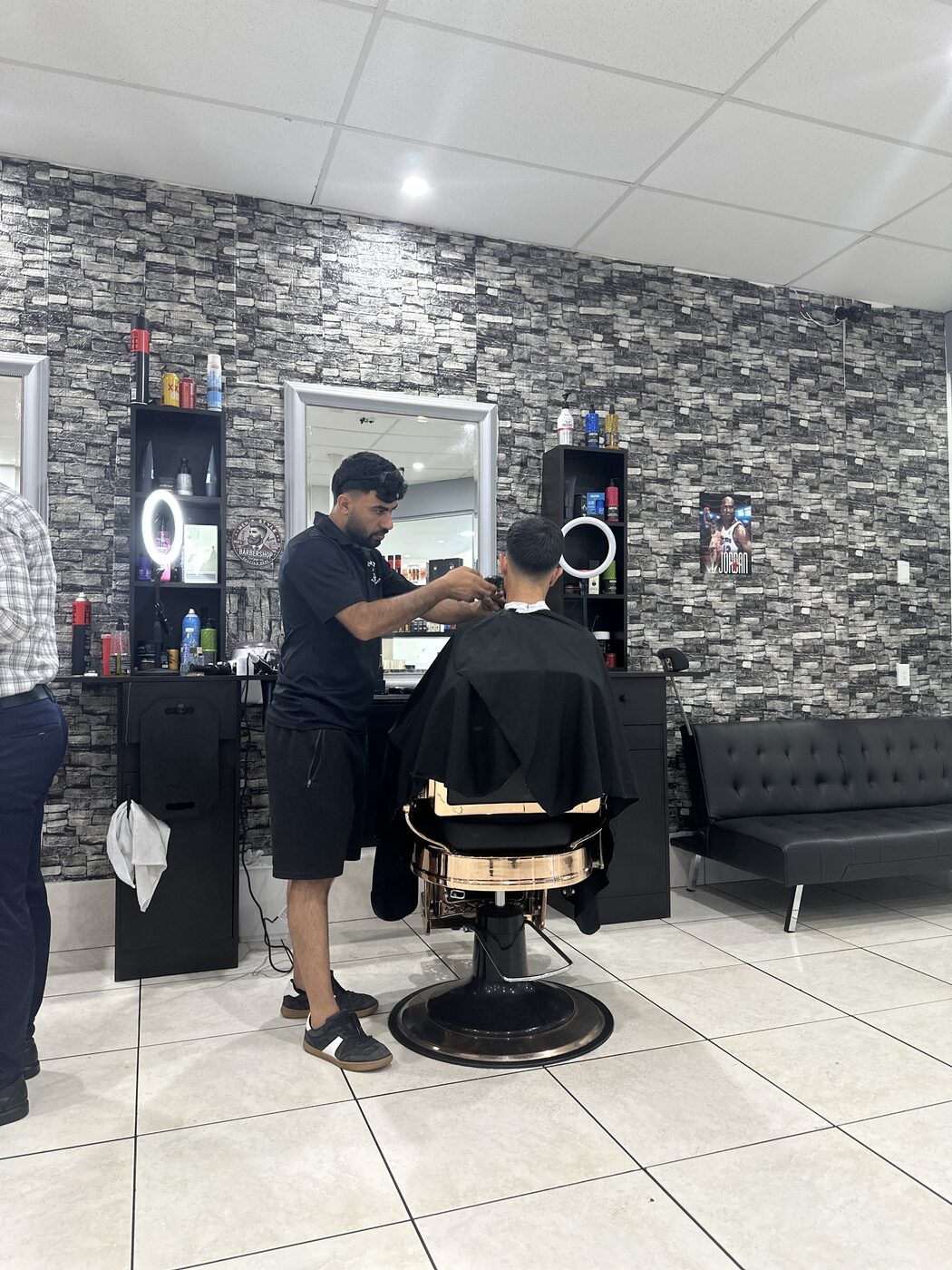 A barber at work on a client in the gold barber chair at Nextcut